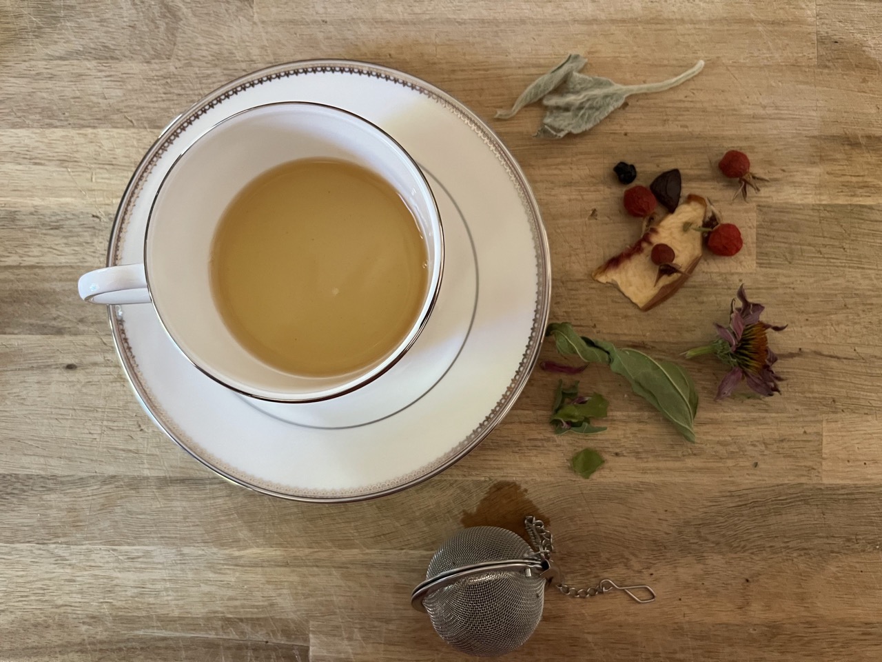 Photo of Tea Cup next to garden herbs.